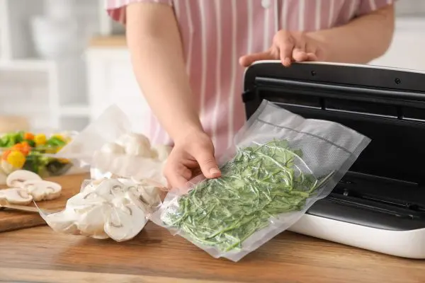 A person vacuum seals some vegetables