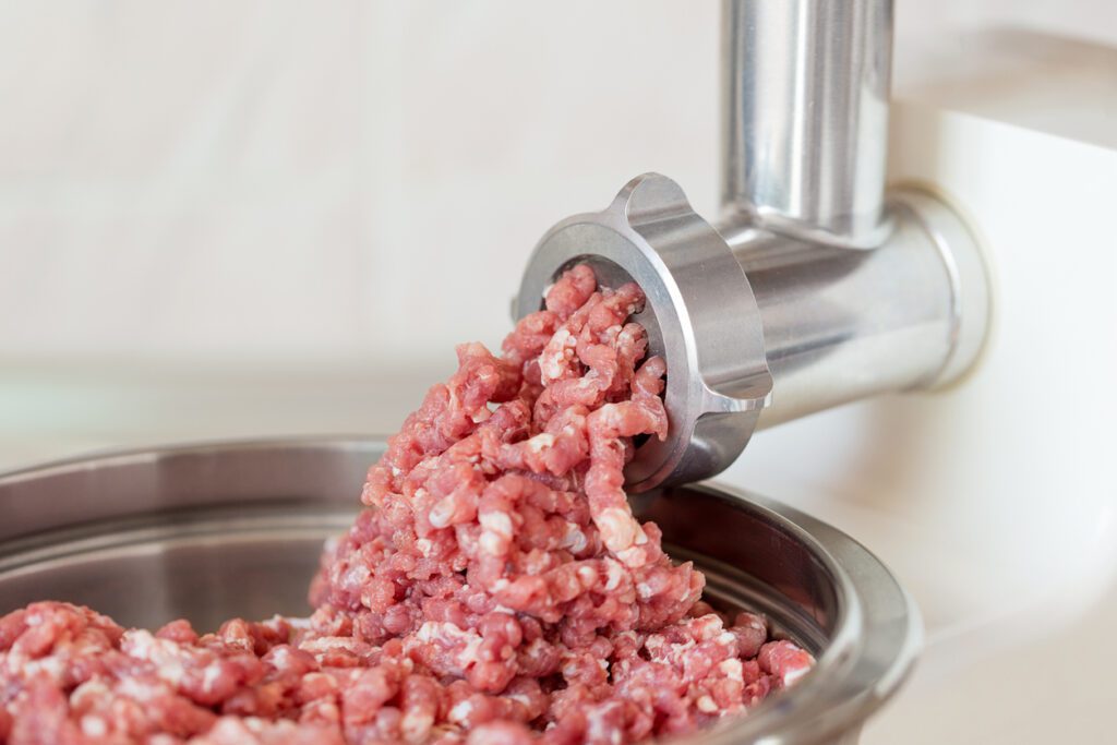 Process of meat grinding in the kitchen with mincing machine.