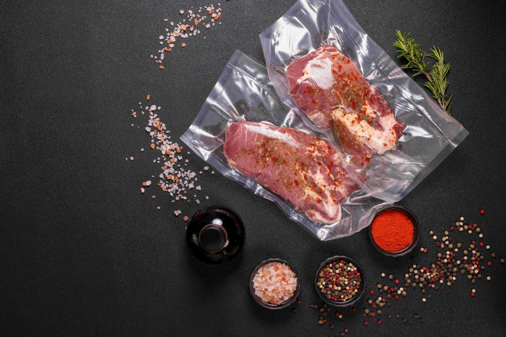 Vacuum‑sealed seasoned meat surrounded by salt, spices, and rosemary